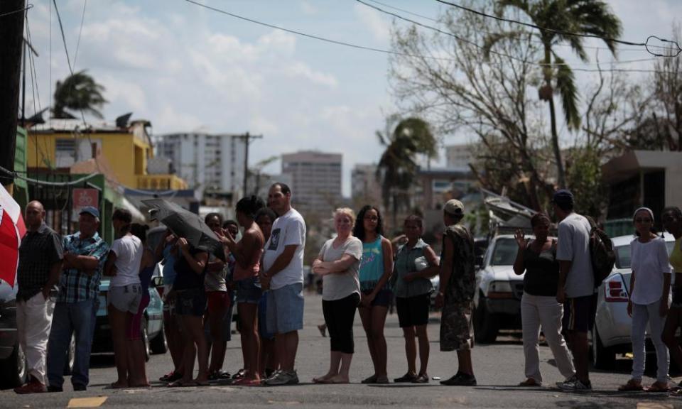 People wait in line for relief items to be distributed in San Juan Sunday.