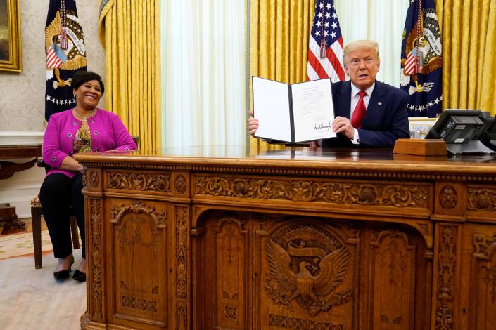 El presidente Donald Trump muestra un indulto completo para Alice Marie Johnson mientras observa en la Oficina Oval el 28 de agosto de 2020.