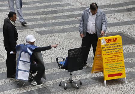 A job promoter points to a list of job offers posted in a main street in downtown Sao Paulo August 13, 2014. REUTERS/Paulo Whitaker