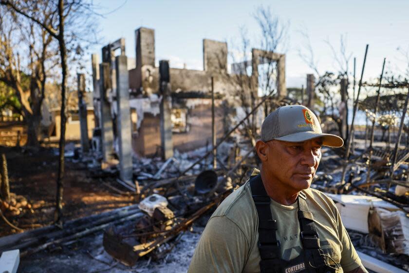 Lahaina, Maui, Monday, August 14, 2023 - Archie Kalepa was in Lake Tahoe when his neighborhood succumbed to flames. He arrived home a day after by boat, fighting overwhelming emotion as he floated toward the smoking rubble of Lahaina.He sits in his backyard that abuts a home that was destroyed in the fire. (Robert Gauthier/Los Angeles Times)