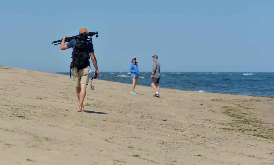 Jesse Mechling, director of marine education for the Center of Coastal Studies carries a pair of binoculars and a scope with him on Wednesday as he walks along High Head Beach in North Truro looking for seals.