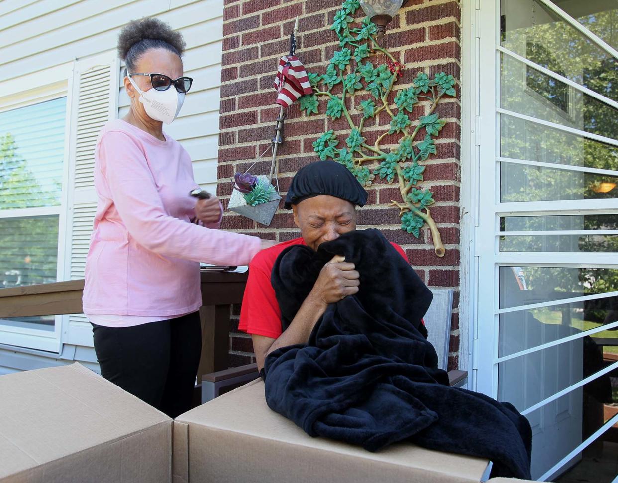 Shirley Walker, left, comforts her neighbor Rebecca Shepard, who reacts to finally receiving items, including the blanket she is holding, that belonged to her son Wesley Shepard, 33, who recently died in Los Angeles. The items were delivered to the wrong address and missing for several weeks.