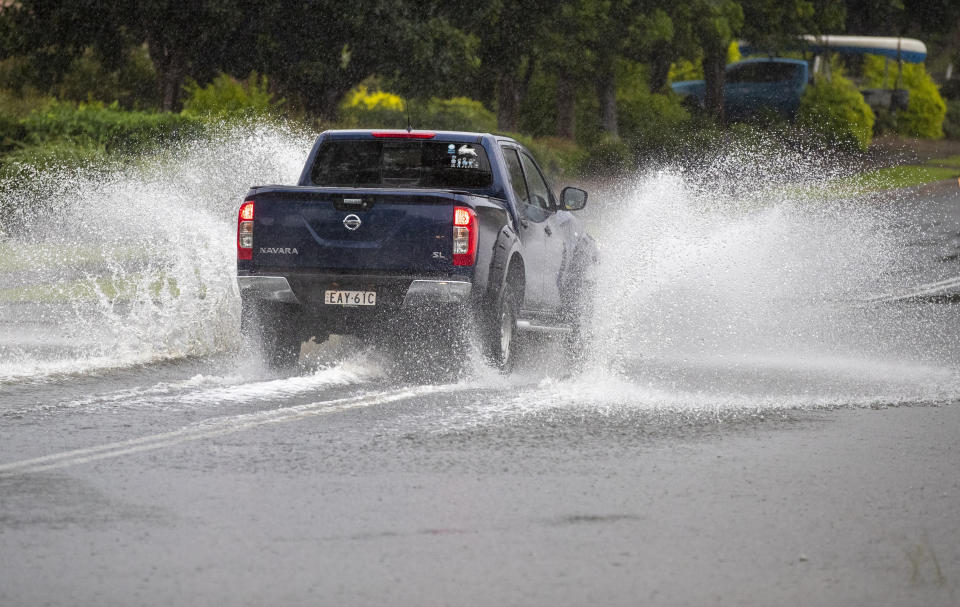 A vehicle plows through water on a flooded road at Port Stephens, 200 kilometers (120 miles) north of Sydney, Australia, Sunday, March 21, 2021. Residents across the state of New South Wales have been warned to prepare for possible evacuations, as NSW Premier Gladys Berejiklian said the state's flood crisis would continue for several more days. (AP Photo/Mark Baker)