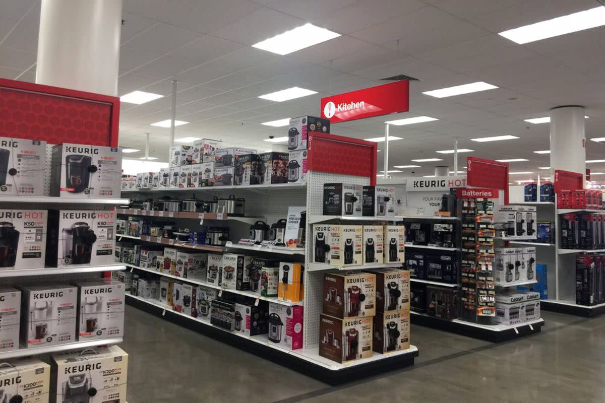 Four aisles in the kitchen department of a Target store, numerous coffee machines and other kitchen appliances neatly arranged on the shelves, clean concrete floor and well lit