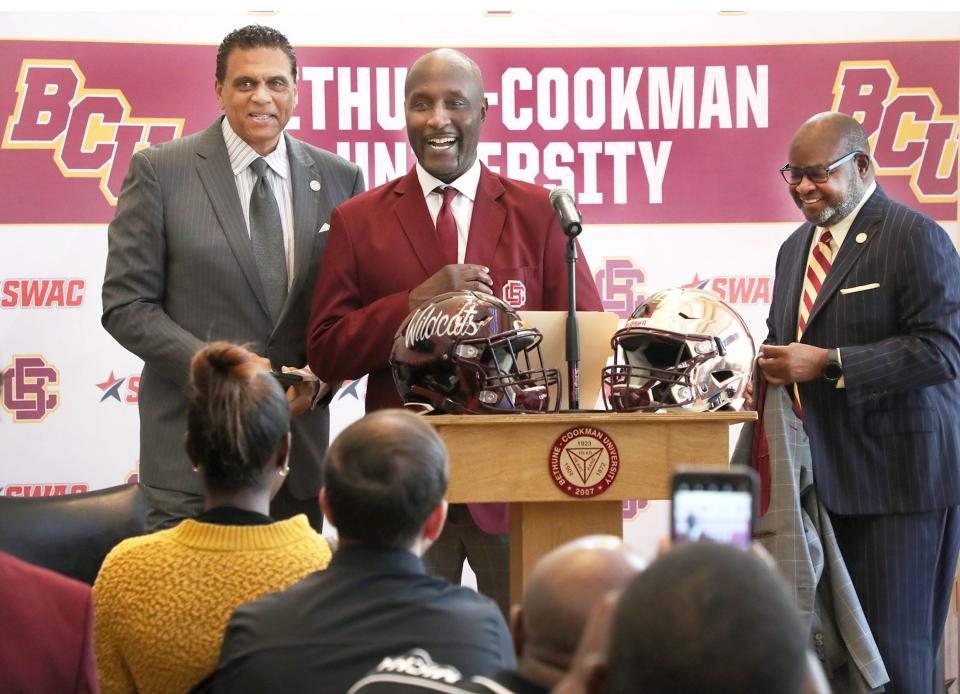 New Bethune-Cookman University head football coach Raymond Woodie smiles after slipping on a B-CU jacket with Athletic Director Reggie Theus and President Lawrence Drake, Wednesday, Feb. 8, 2023 during a press conference in the Larry R. Handfield Athletic Training Center.