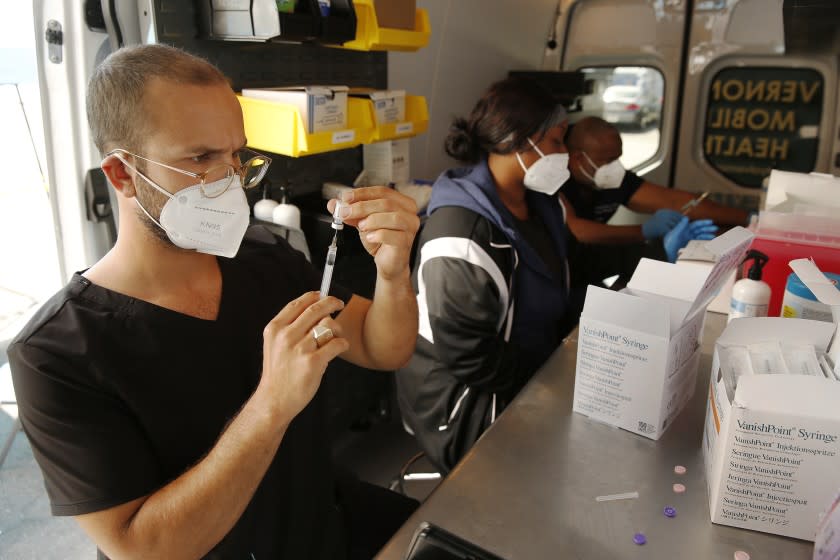 VERNON, CA - MARCH 17: Emergency Medical Technician Lenny Fernandez, Medical Assistant Rodnay Moore and Physician Assistant-Certified Calvin Davis, left to right, prepare doses of the Pfizer COVID vaccine in theVernon City van as the city of Vernon Health Department staff used the city's new mobile health unit clinic to administer COVID-19 vaccinations to nearly 250 essential food processing workers at Rose & Shore, Inc., a major, locally-based prepared foods products producer that serves supermarkets, schools, restaurants, airlines and others. The vaccinations were administered onsite, at the company's 70,000 square foot facility in Vernon. The City of Vernon has partnered with Stacy Medical Center to vaccinate 11,000 Vernon- based workers performing essential jobs in high-density work environments such as large-scale food processing, cold storage and food warehousing facilities. Vernon City Administrator Carlos R. Fandino, Jr. said, "The City of Vernon has taken a pro-active stance to protect the community from COVID-19. Vernon's Health Department has mobilized to deliver life-saving COVID vaccines to essential workers who put their lives on the line producing food and everyday items. Vernon's businesses are pleased that the city now has the mobile health clinic to help protect their essential employees against the potentially deadly coronavirus and mitigate the virus's spread at their processing plants. Administering COVID-19 vaccines to their workers while they're on- the-job ensures accessibility for a population that is largely underserved and the hardest hit by the pandemic." "Our mobile delivery method is extremely efficient. Vernon's Health Department has inoculated over 3,000 essential workers in its initial thirteen days of operation, with another 1,000 expected this week as the mobile vaccine unit visits additional plants daily. We are vaccinating as quickly as state and county public health officials provide us with vaccines." Mr. Fandino said. Rose & Shore, Inc on Wednesday, March 17, 2021 in Vernon, CA. (Al Seib / Los Angeles Times).