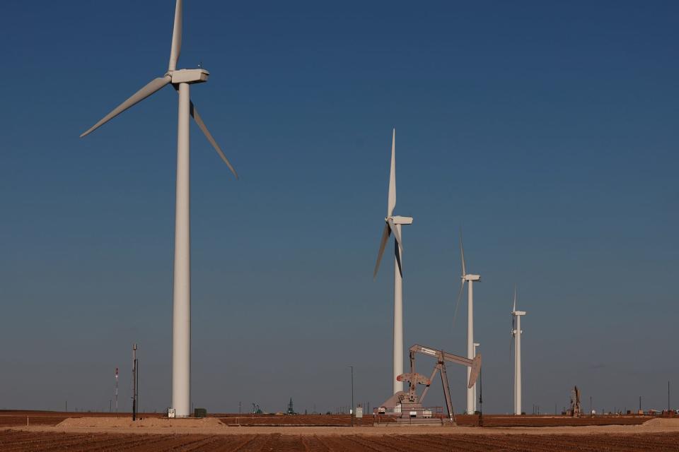 An oil pumpjack works near wind turbines in the Permian Basin oil field in Stanton, Texas, on March 11, 2022.<span class="copyright">Joe Raedle—Getty Images</span>