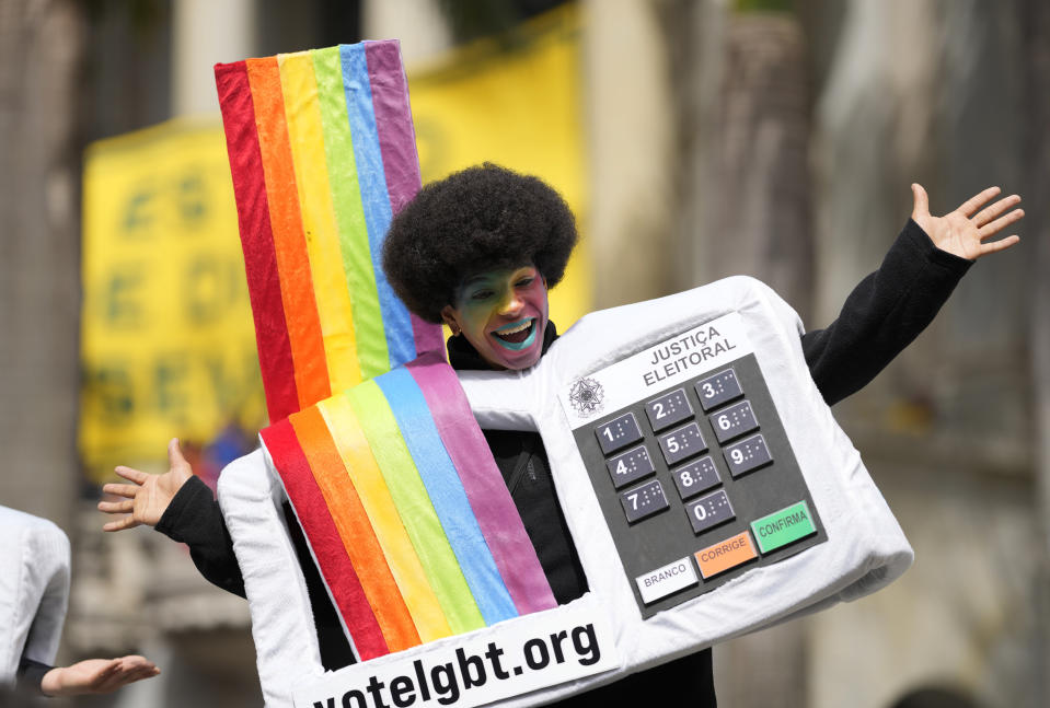 An LGBT activist wearing a costume in the likeness of an electronic voting machine gathers with others after the reading of two manifestos defending the nation's democratic institutions and electronic voting system outside the Faculty of Law at Sao Paulo University in Sao Paulo, Brazil, Thursday, Aug. 11, 2022. The two documents are inspired by the original "Letter to the Brazilians" from 1977 denouncing the brutal military dictatorship and calling for a prompt return of the rule of law. (AP Photo/Andre Penner)