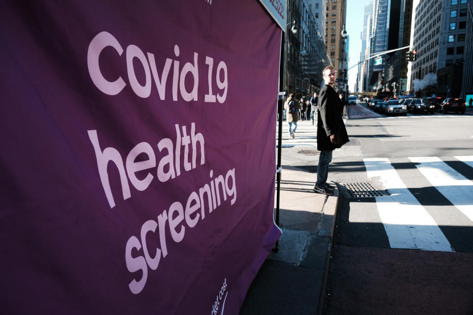 A pedestrian waits at an intersection by a COVID-19 testing site.