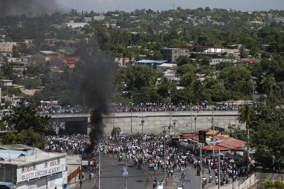 Protesters led by the art community demand the resignation of Haitian President Jovenel Moise as they march through Port-au-Prince, Haiti, some having set debris on fire, Sunday, Oct. 13, 2019. Protests have paralyzed the country for nearly a month, shuttering businesses and schools. (AP Photo/Rebecca Blackwell)