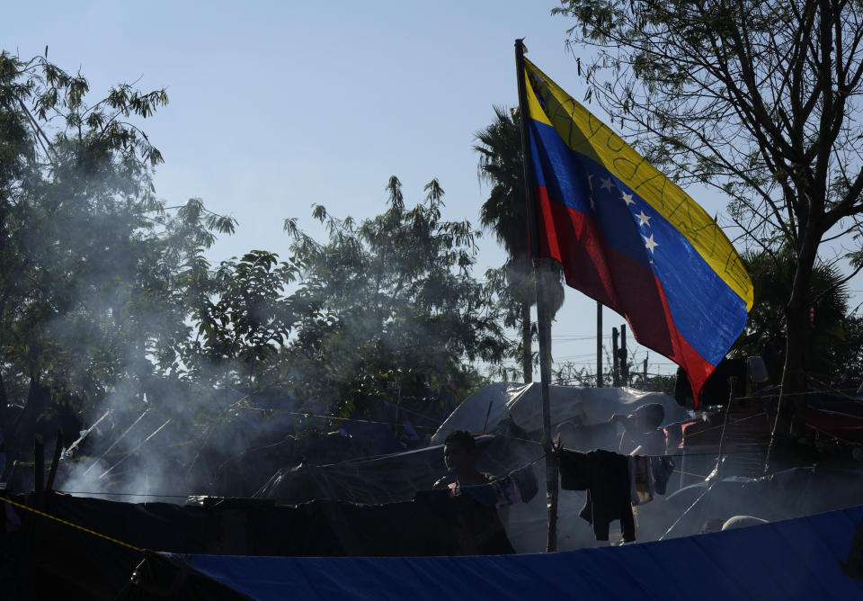 A Venezuelan national flag marked with a message that reads in Spanish: "Help me," is flown over a tent at a makeshift camp of migrants set up along a river bank in Matamoros, Mexico, Thursday, Dec. 22, 2022. (AP Photo/Fernando Llano)