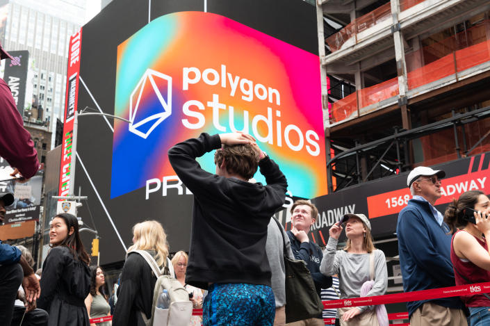 NEW YORK, NEW YORK - JUNE 23: People walk by a Polygon Studios billboard in Times Square during the 4th annual NFT.NYC conference on June 23, 2022 in New York City. The four-day event featured 1,500 speakers from the crypto and NFT space with over 14,000 guests in attendance. (Photo by Noam Galai/Getty Images)