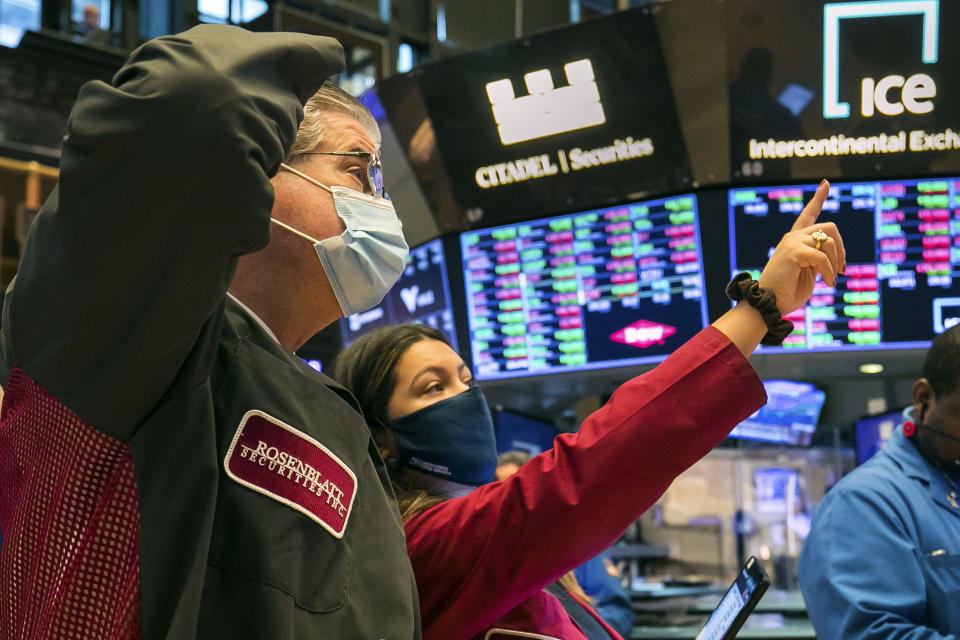 In this photo provided by the New York Stock Exchange, trader Ashley Lara works with a colleague on the floor Friday, Nov. 20, 2020. U.S. stocks are pulling a bit lower in midday trading Friday as worries about the worsening pandemic weigh on rising optimism about a coming coronavirus vaccine. (Courtney Crow/New York Stock Exchange via AP)