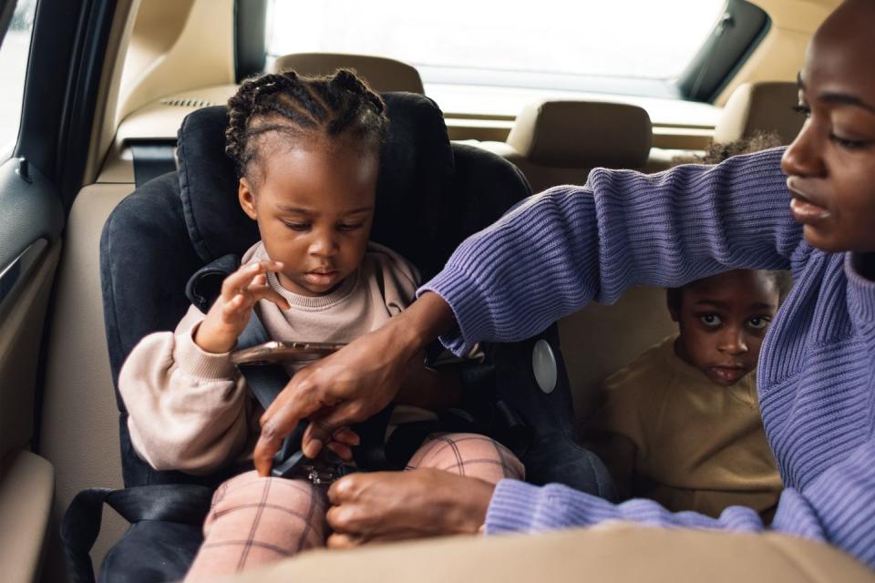 mom buckling child into car seat