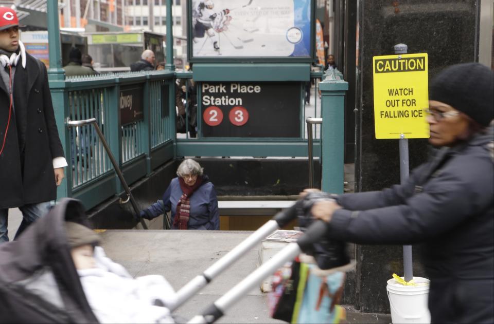 Pedestrians pass a sign warning them of falling ice Tuesday, Feb. 18, 2014, in New York. Amid a brutal winter, New Yorkers are battling something far more dangerous than snow falling from the sky: ice tumbling from skyscrapers. (AP Photo/Frank Franklin II)