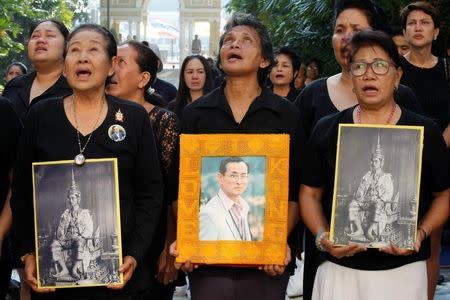 People hold portraits of Thailand's late King Bhumibol Adulyadej as they sing a national anthem at the Siriraj hospital in Bangkok, Thailand, October 14, 2016. REUTERS/Chaiwat Subprasom