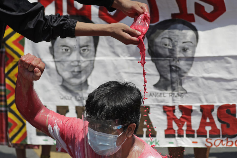 A protester pours red paint on another to symbolize killings as they hold a rally outside the Malacanang palace in Manila, Philippines on Wednesday, June 30, 2021. The group has called for justice and accountability for the thousands who have died due to the government's anti-drug crackdown under the Duterte administration. (AP Photo/Aaron Favila)