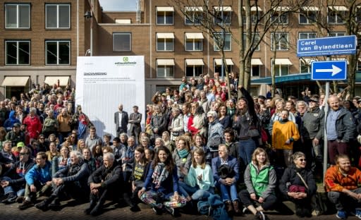 Dozens of activists sit and stand outside Shell's base in The Hague, where they handed the oil giant a lawsuit aimed at forcing it to meet targets in the Paris accord