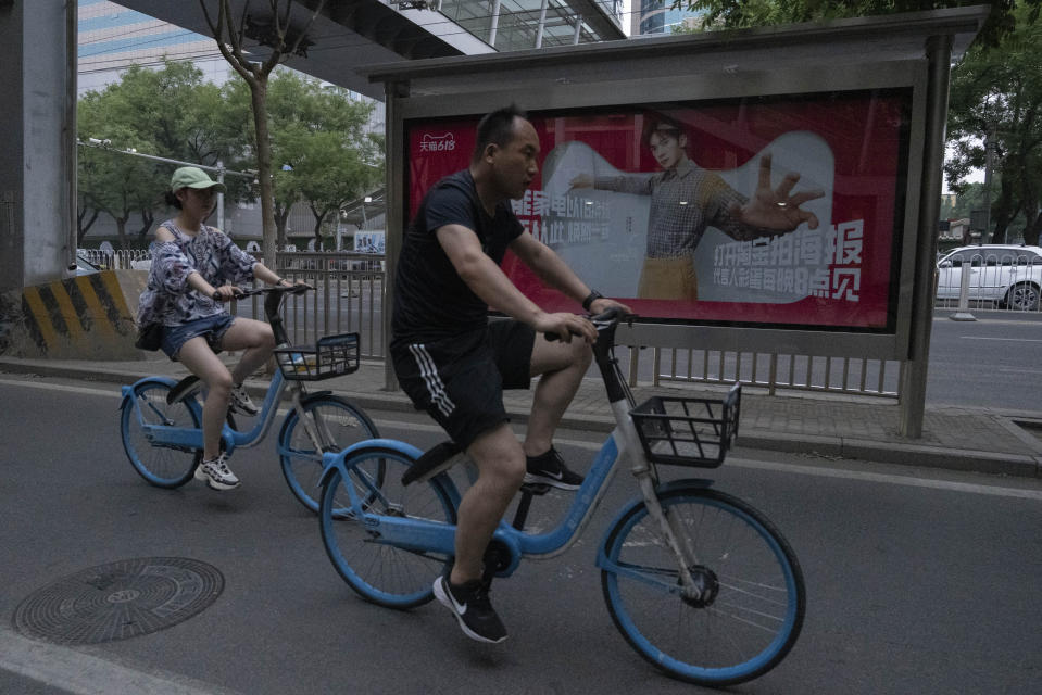 Cyclists ride past an advertisement for the annual June 18 Shopping festival in Beijing, Sunday, June 18, 2023. Chinese merchants offered customers steep discounts during China's first major online shopping festival after the COVID-19 pandemic, in the hopes of shoring up sales amid a weaker-than-expected recovery in consumption. (AP Photo/Ng Han Guan)