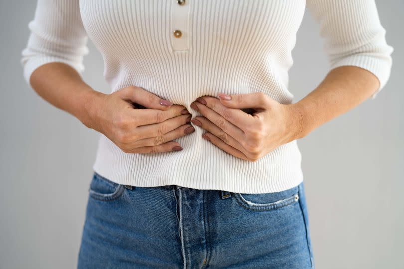 A woman holding her stomach in discomfort