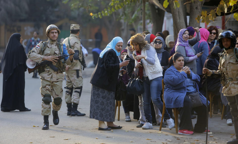Egyptian army soldiers stand guard as voters line up outside a polling station in Cairo, Egypt, Tuesday, Jan. 14, 2014. Egyptians have started voting on a draft for their country's new constitution that represents a key milestone in a military-backed roadmap put in place after President Mohammed Morsi was overthrown in a popularly backed coup last July. (AP Photo/Amr Nabil)