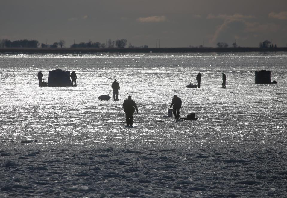 People make their way out onto the ice to fish on the frozen Lake St. Clair in Ira Township on December 28, 2017.