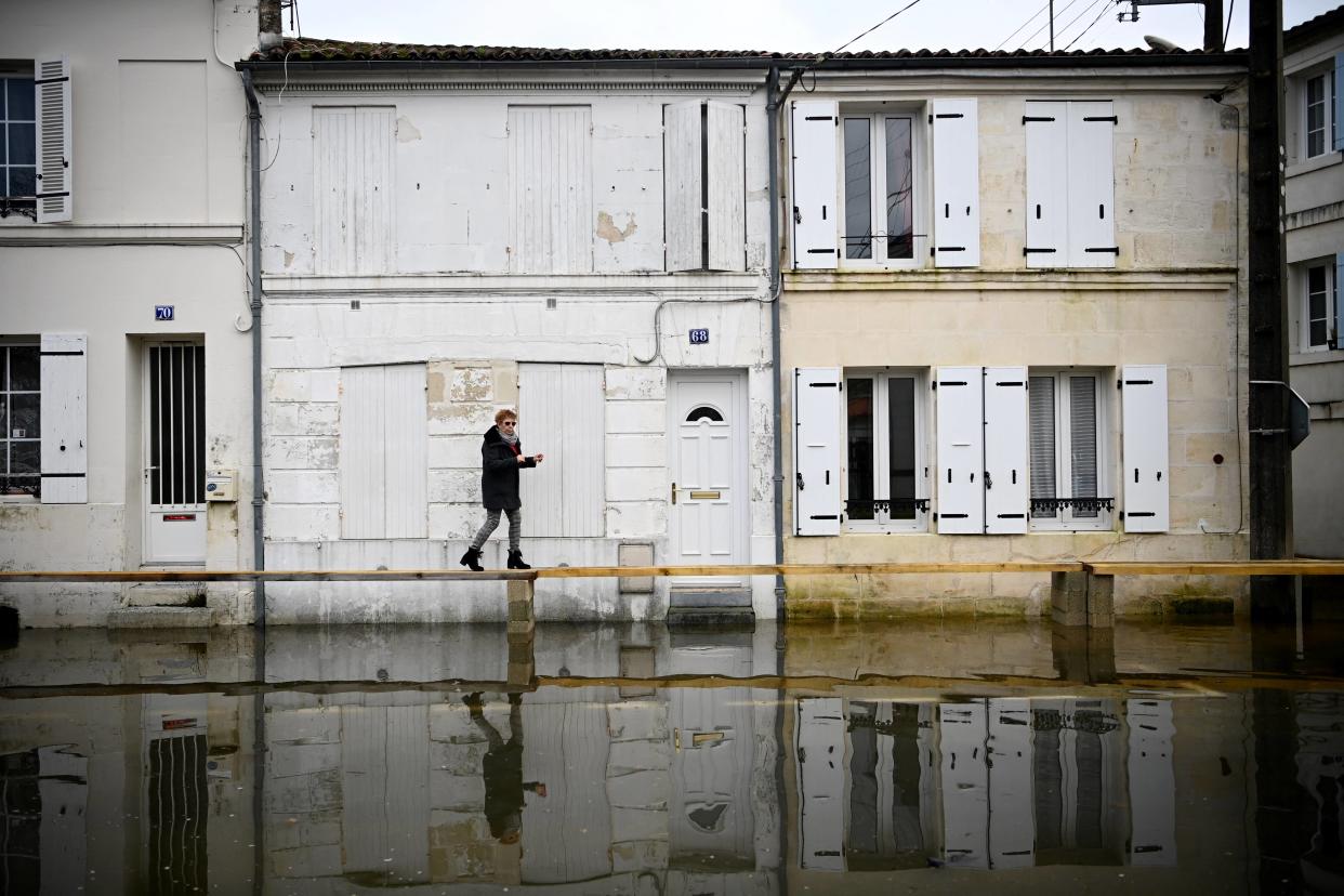 Une femme marche sur un pont en bois installé dans les rues lors de l’inondation de la Charente dans la ville de Saintes, le 15 décembre 2023.