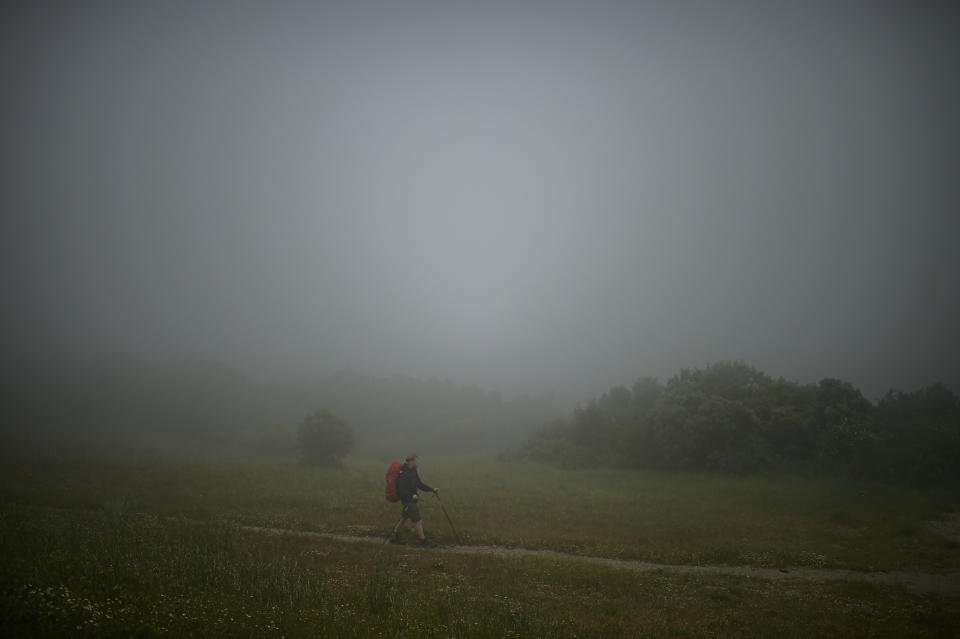 A pilgrim makes the St. James' Way walking at El Perdon mountain, near to Pamplona northern northern Spain, Tuesday, June 1, 2021. The pilgrims are trickling back to Spain's St. James Way after a year of being kept off the trail due to the pandemic. Many have committed to putting their lives on hold for days or weeks to walk to the medieval cathedral in Santiago de Compostela in hopes of healing wounds caused by the coronavirus. (AP Photo/Alvaro Barrientos)