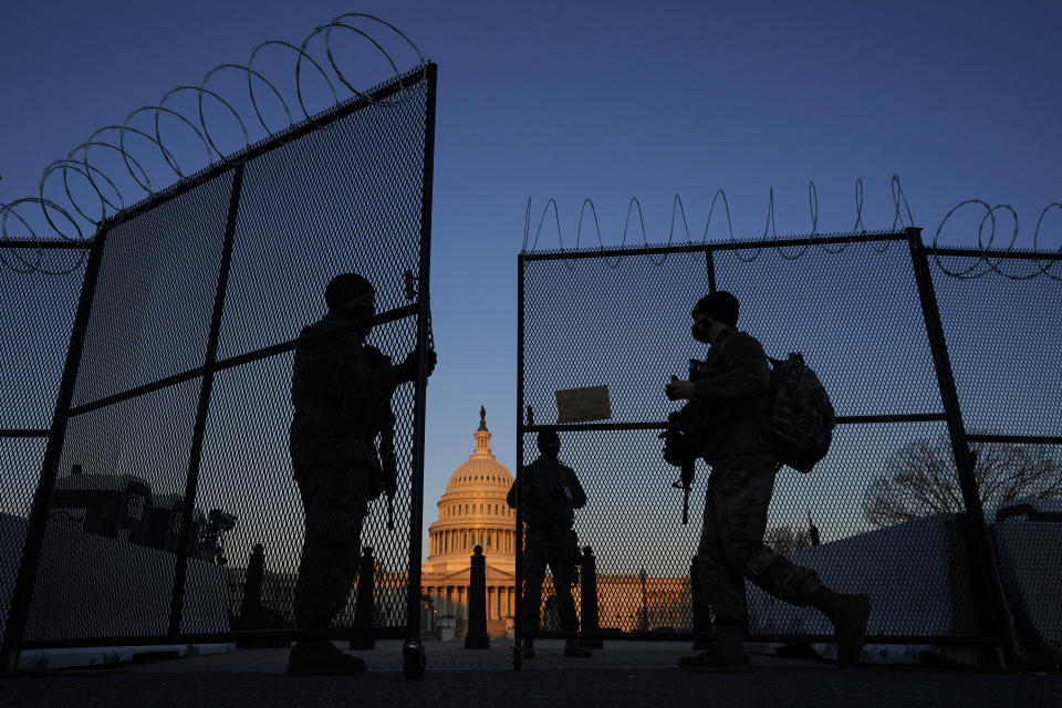 National Guard soldiers open a gate of the razor wire-topped perimeter fence around the Capitol to allow a colleague in at sunrise in Washington, Monday, March 8, 2021. (AP Photo/Carolyn Kaster)