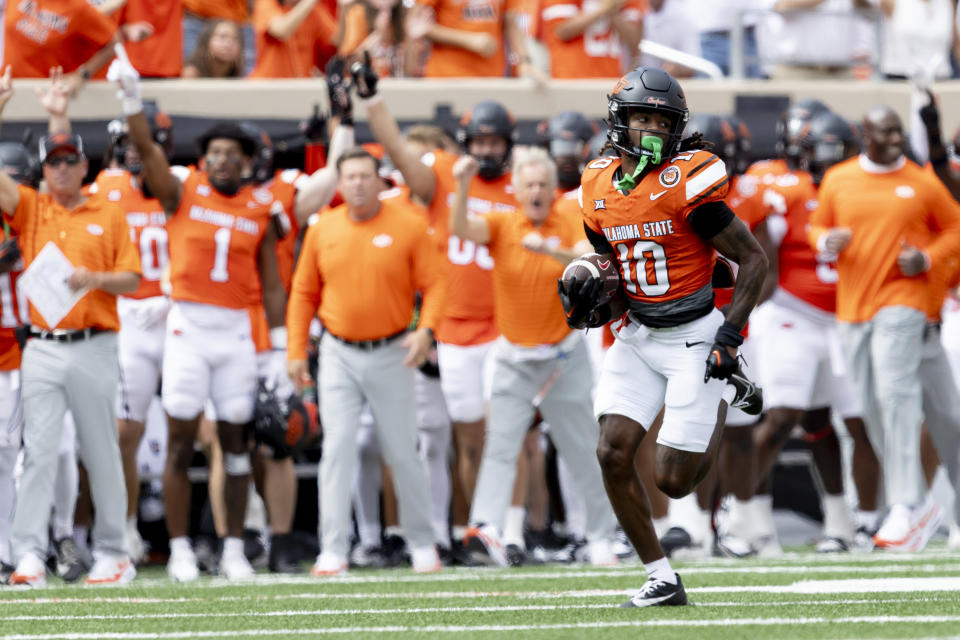 Oklahoma State cornerback Kale Smith (10) retourneert een onderschepping voor een touchdown in de eerste helft van een NCAA universiteitsvoetbalwedstrijd tegen Arkansas, zaterdag 7 september 2024, in Stillwater, Oklahoma. (AP Foto/Mitch Alcala)