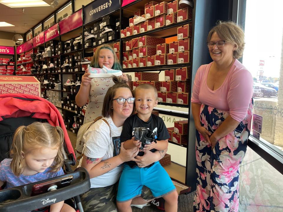Charlie Hill with her son Charles Hill, 4, sitting on her lap showing off his new pair of shoes alongside his sister Hailee Hill, 9, who also got a new pair of shoes during the 2021 Cents for Shoes initiative.