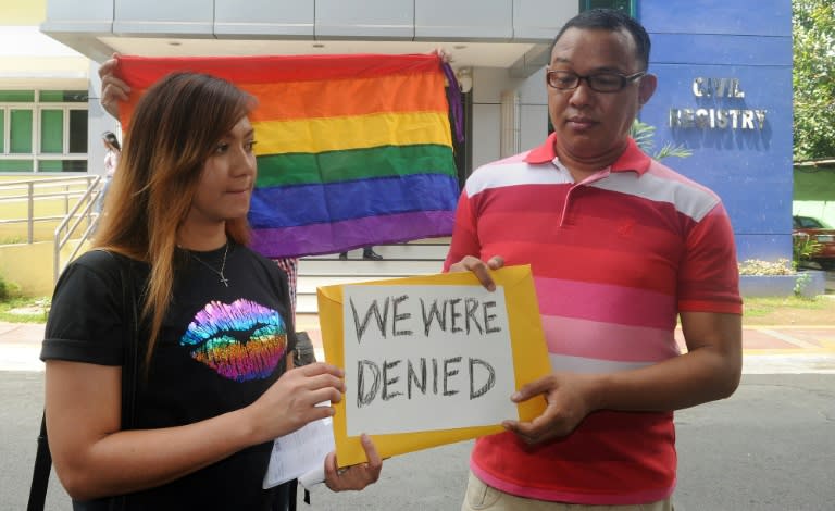 Maria Arlyn Ibanez (L) and pastor Crescencio Agbayani (R) hold a placard in protest outside the Civil Registry Office in Manila on August 3, 2015, after their application for same-sex marriage licenses for their respective partners were denied