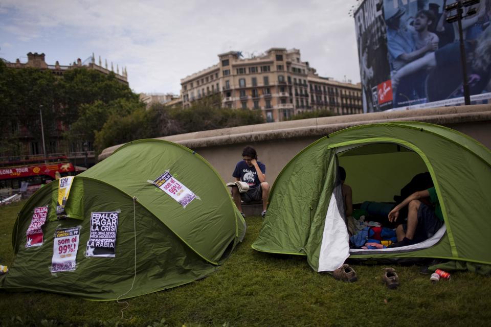 Albert, 19, reads a book next to his tent after spending the night at the Catalunya square during a protest to mark the anniversary of the "Indignados" movement in Barcelona, Spain, Sunday May 13, 2012. Spaniards angered by increasingly grim economic prospects and unemployment hitting one out of every four citizens protested in droves Saturday in the nation's largest cities, marking the one-year anniversary of a spontaneous movement that inspired similar anti-authority demonstrations across the planet. (AP Photo/Emilio Morenatti)