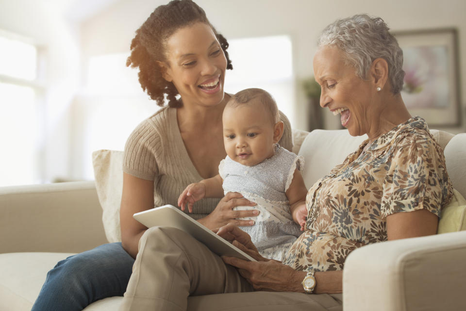 Three generations of women using digital tablet on sofa