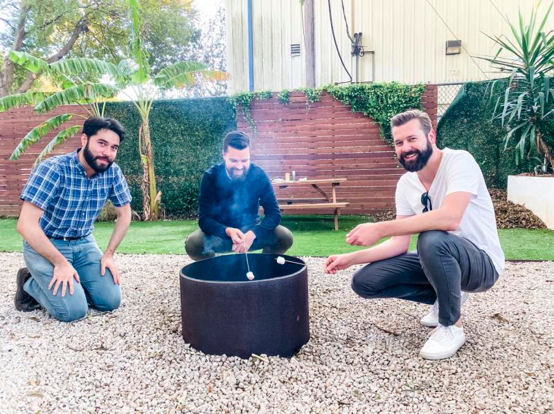 Spruce executives Ed Ryan, Paul Clark, and Rick Ford, roast marshmallows outside their headquarters during a recent happy hour. The Austin, Texas-based startup is among many companies debating whether to continue certain perks such as snacks and meals as several employees return back to the office.