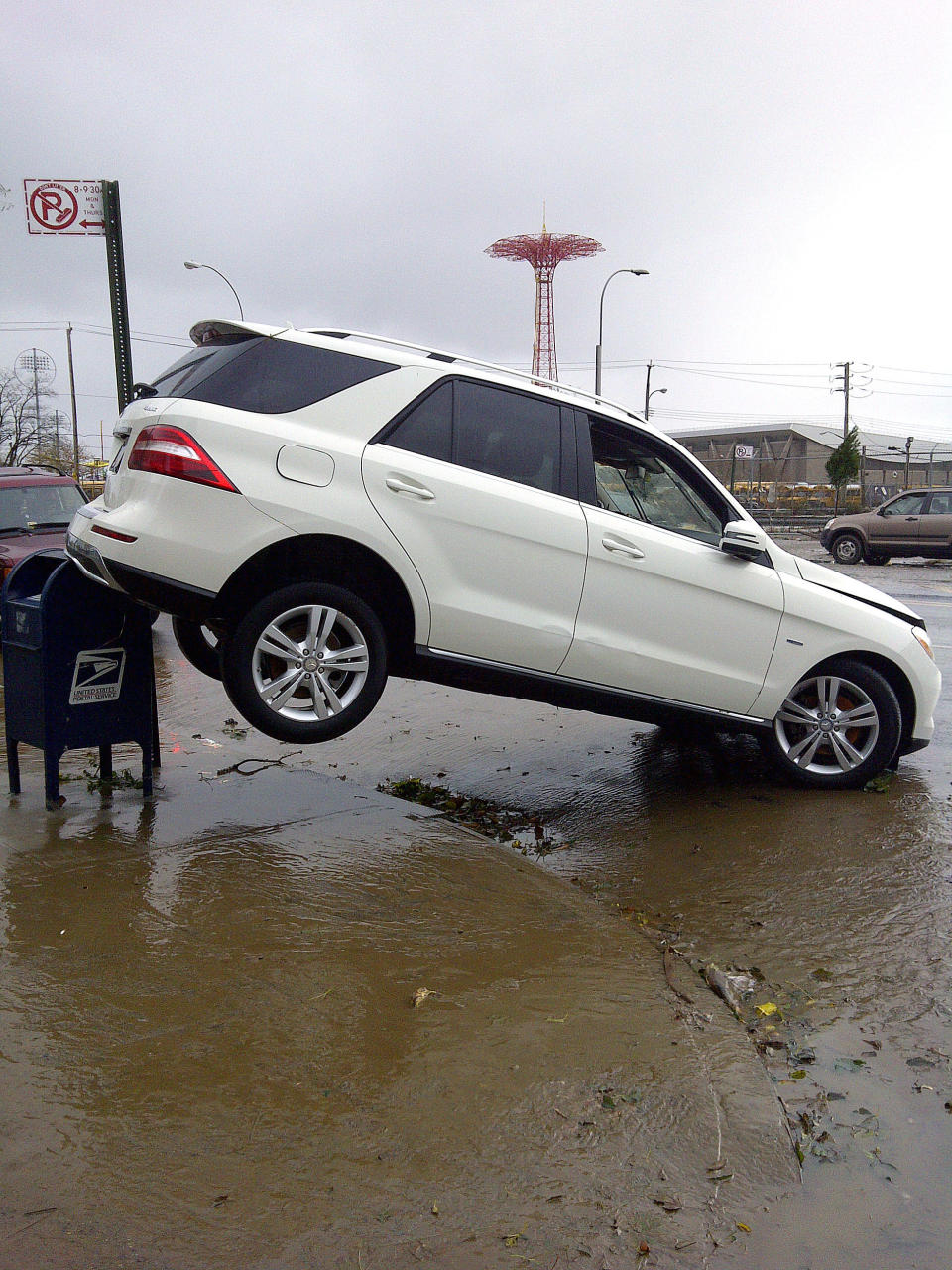A car is upended on a mailbox on Surf Avenue in Coney Island, N.Y., in the aftermath of Sandy on Tuesday, Oct. 30, 2012. Sandy, the storm that made landfall Monday, caused multiple fatalities, halted mass transit and cut power to more than 6 million homes and businesses. (AP Photo/Ralph Russo)