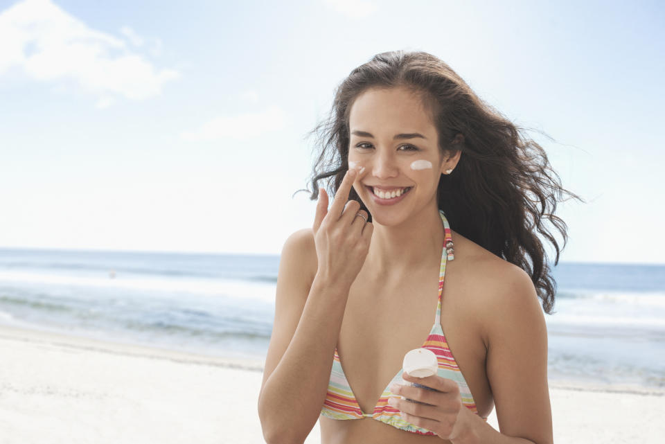 Woman applying sunscreen on beach. (PHOTO: Getty Images)