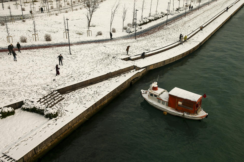 People walk over the Golden Horn at Istanbul, Tuesday, Jan. 25, 2022. Rescue crews in Istanbul and Athens on Tuesday cleared roads that had come to a standstill after a massive cold front and snowstorms hit much of Turkey and Greece, leaving countless people and vehicles in both cities stranded overnight in freezing conditions.(AP Photo/Emrah Gurel)