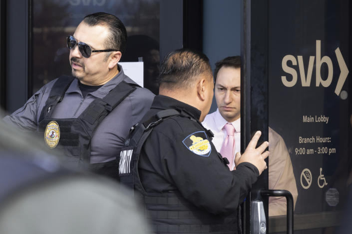 Igor Fayermark, right, from the Federal Deposit Insurance Corporation (FDIC), exits Silicon Valley Bank&#39;s headquarters in Santa Clara, Calif., on Monday, March 13, 2023. The federal government intervened Sunday to secure funds for depositors to withdraw from Silicon Valley Bank after the bank&#39;s collapse. Dozens of individuals waited in line outside the bank to withdraw funds. (AP Photo/Benjamin Fanjoy)