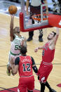 Boston Celtics' Jeff Teague (55) shoots over Daniel Gafford (12) and Tomas Satoransky during the first half of an NBA basketball game Monday, Jan. 25, 2021, in Chicago. (AP Photo/Charles Rex Arbogast)