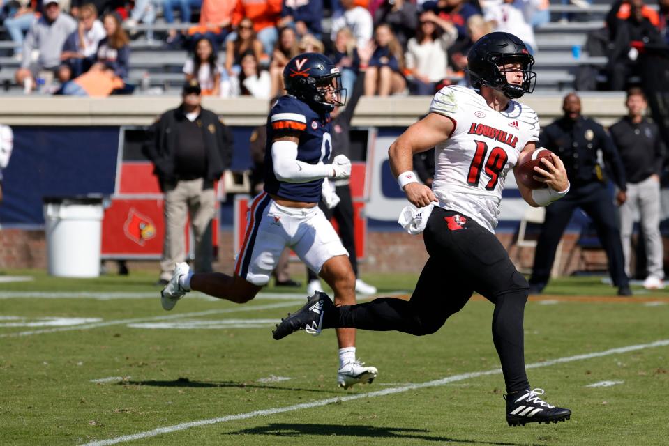 Oct 8, 2022; Charlottesville, Virginia, USA; Louisville Cardinals quarterback Brock Domann (19) scores a touchdown as Virginia Cavaliers safety Antonio Clary (0) chases during the second quarter at Scott Stadium. Mandatory Credit: Geoff Burke-USA TODAY Sports