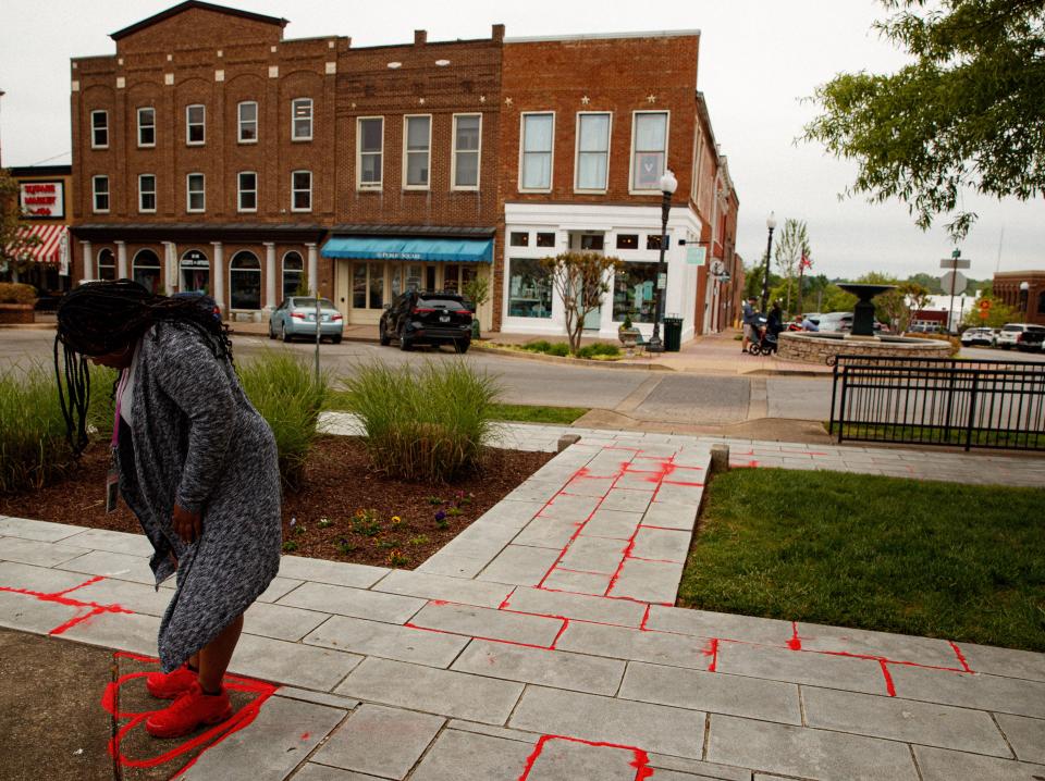Jennifer Kinzer Parks, public health educator to Maury County Health Department, stands in the center of a heart drawn in red sand following a Red Sand Project event in Columbia, Tenn. on Apr. 27, 2023. 