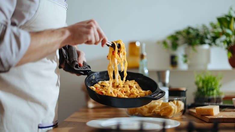 Chef holding pan of pasta in vodka sauce
