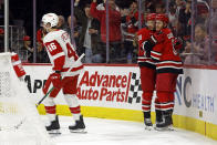 Carolina Hurricanes' Sebastian Aho, center, celebrates his goal with teammate Jake Guentzel as Detroit Red Wings' Jeff Petry (46) skates by during the second period of an NHL hockey game in Raleigh, N.C., Thursday, March 28, 2024. (AP Photo/Karl B DeBlaker)