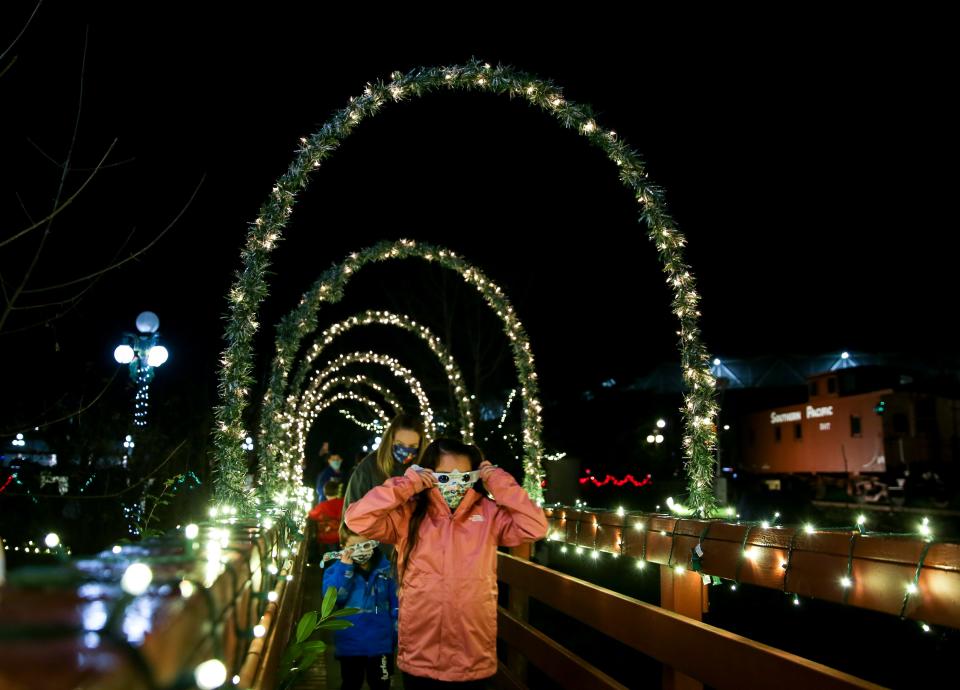 Families walk through a tunnel of lights at Magic at the Mill in 2021.