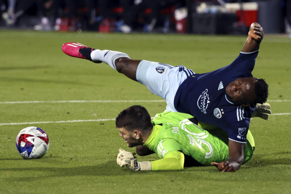 Dallas goalkeeper Maarten Paes (30) collides with Sporting Kansas City forward Willy Agada (23) while trying to stop a shot in the second half of an MLS soccer match, Saturday, March 18, 2023, in Frisco, Texas. (AP Photo/Richard W. Rodriguez)