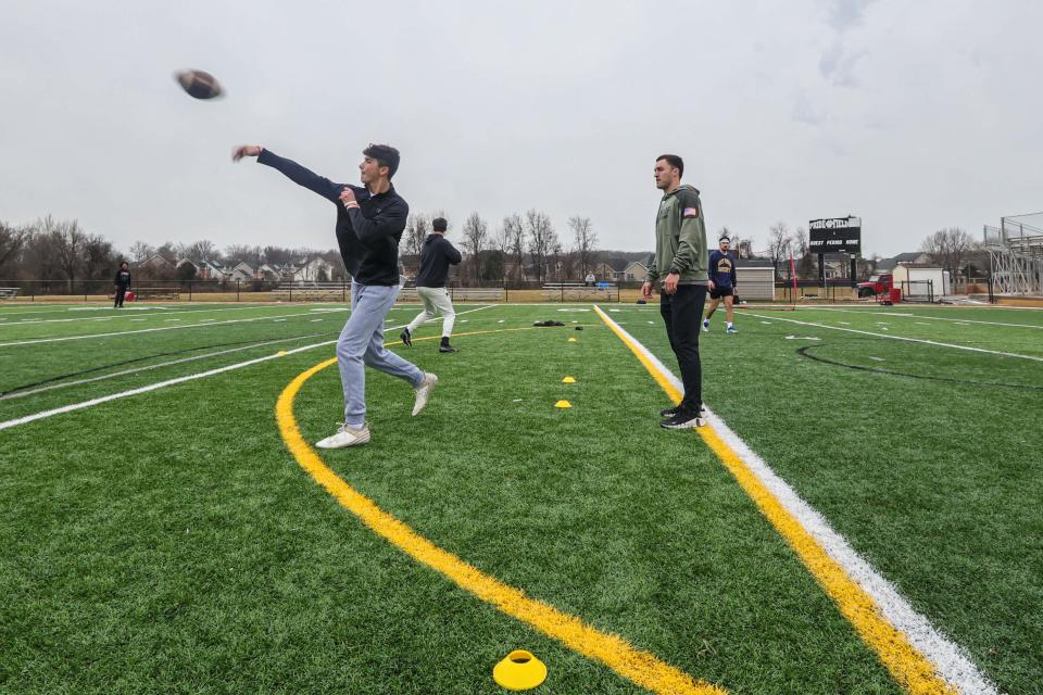 Former Smyrna High and University of Delaware quarterback Nolan Henderson (right) looks on as current Smyrna Eagles Quarterback Drew Marks throws the ball during a quarterbacks training session on Sunday, February 11, 2024.