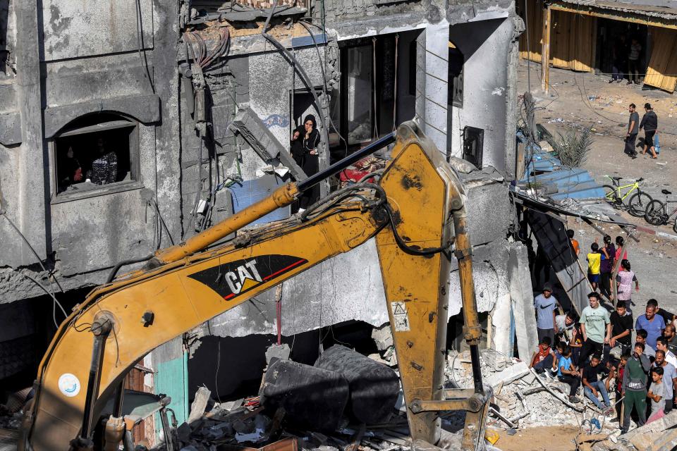 People look on as an excavator clears rubble after a building was hit by Israeli bombardment in Rafah in the southern Gaza Strip on Tuesday (AFP via Getty Images)