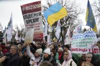 Demonstrators hold anti-vax posters, one in the center reading "the epidemic is a lie, the world conspiracy against the god" during a protest against COVID-19 restrictions and vaccine mandates in Kyiv, Ukraine, Wednesday, Nov. 3, 2021. In a bid to stem contagion, Ukrainian authorities have required teachers, government employees and other workers to get fully vaccinated by Nov. 8 or face having their salary payments suspended. In addition, proof of vaccination or a negative test is now required to board planes, trains and long-distance buses. (AP Photo/Efrem Lukatsky)