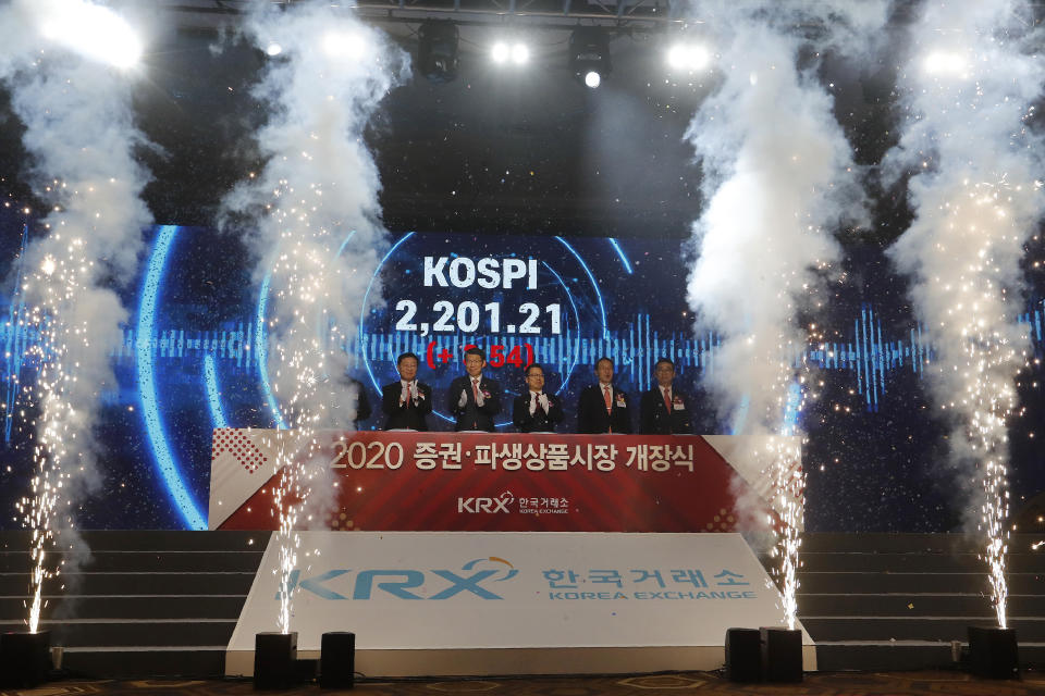 Jung Ji-won, third from left, chief executive of the Korea Exchange, and Financial Services Commission Chairman Eun Sung-soo, fourth from left, applaud with other participants during the opening of this year's trading in Seoul, South Korea, Thursday, Jan. 2, 2020. The sign read: "Opening ceremony of 2020 trading." (AP Photo/Ahn Young-joon)